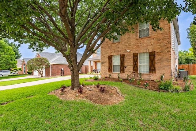 view of front of property with driveway, a front yard, central AC, and brick siding