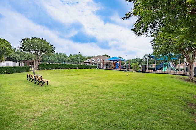 view of property's community with fence, playground community, and a yard