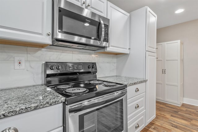 kitchen with appliances with stainless steel finishes, white cabinets, and light wood-style flooring