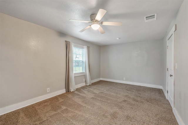 carpeted empty room with ceiling fan, visible vents, and baseboards