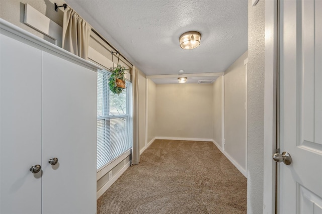 interior space featuring a textured ceiling, carpet flooring, visible vents, and baseboards