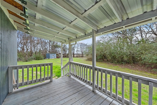 wooden terrace featuring a storage unit, an outdoor structure, and a yard