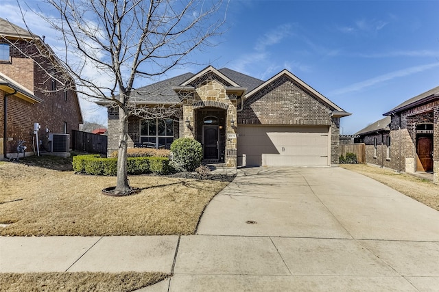 french country home featuring driveway, stone siding, an attached garage, cooling unit, and brick siding