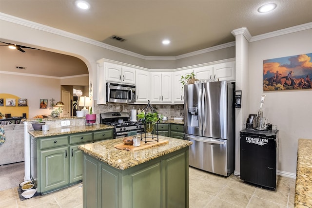 kitchen with green cabinets, stainless steel appliances, arched walkways, and white cabinets