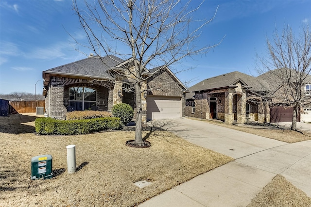 french provincial home featuring a garage, brick siding, fence, driveway, and roof with shingles