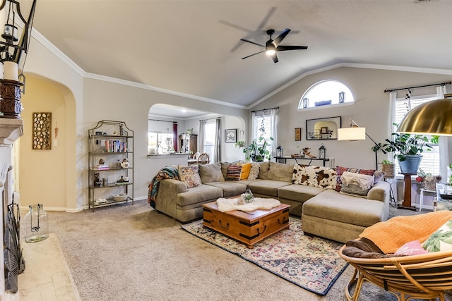 carpeted living area with arched walkways, ceiling fan, baseboards, vaulted ceiling, and ornamental molding