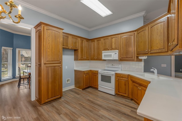 kitchen with a chandelier, white appliances, a sink, and wood finished floors