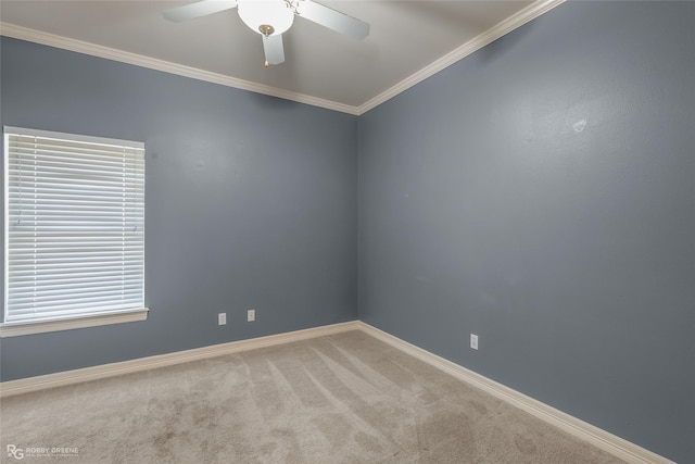 carpeted empty room featuring a ceiling fan, baseboards, and crown molding