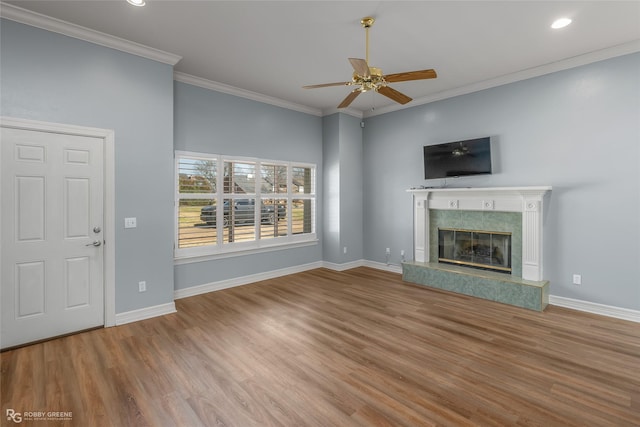 unfurnished living room featuring a fireplace, ornamental molding, a ceiling fan, wood finished floors, and baseboards