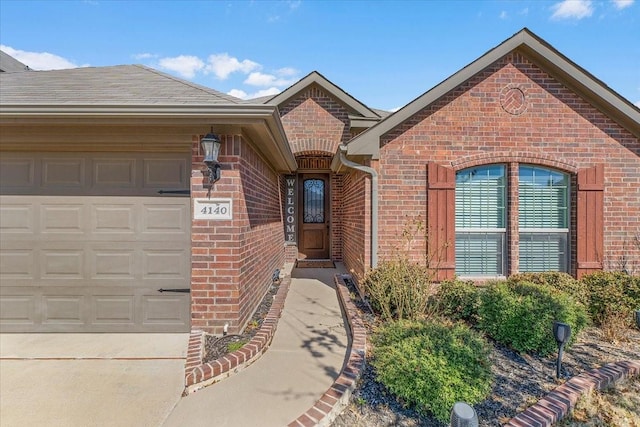 entrance to property featuring a garage, brick siding, and a shingled roof