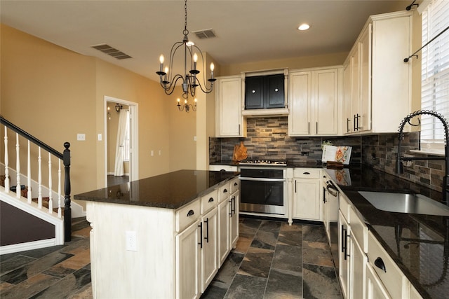 kitchen featuring visible vents, stainless steel appliances, stone finish flooring, and a sink