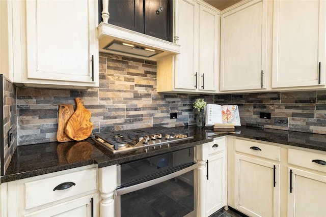 kitchen featuring under cabinet range hood, backsplash, dark stone countertops, and appliances with stainless steel finishes