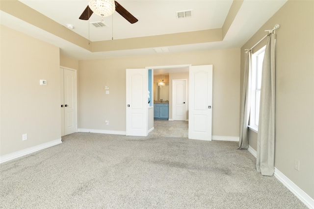 interior space featuring ceiling fan, a raised ceiling, visible vents, and light carpet