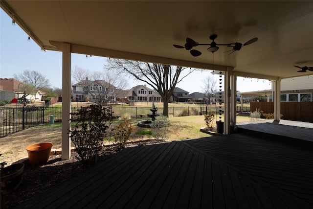 wooden deck featuring a residential view, ceiling fan, and a fenced backyard