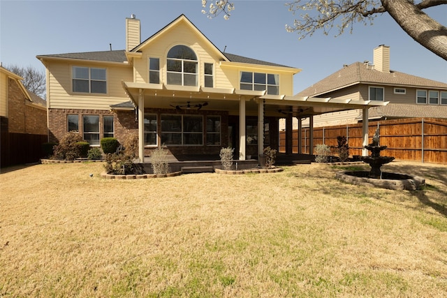 rear view of house featuring a lawn, fence, ceiling fan, a chimney, and a patio area