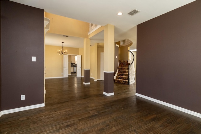 spare room featuring visible vents, stairway, baseboards, a chandelier, and dark wood-style flooring