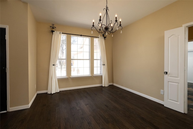 spare room with baseboards, dark wood-type flooring, and a chandelier