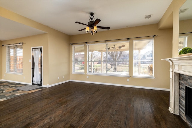 unfurnished living room with visible vents, a ceiling fan, a fireplace, baseboards, and dark wood-style flooring