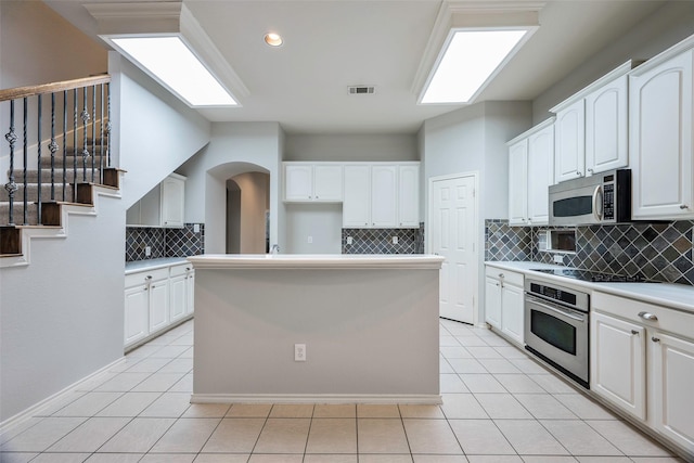 kitchen with a center island, visible vents, appliances with stainless steel finishes, white cabinetry, and light tile patterned flooring