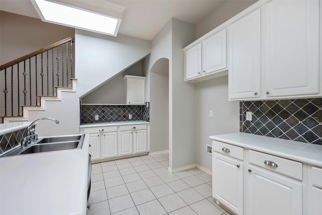 kitchen with light countertops, white cabinets, a sink, and light tile patterned flooring