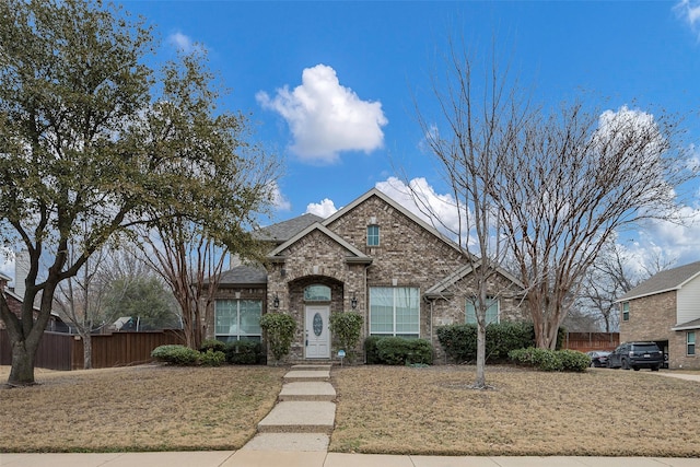 view of front of house featuring fence and brick siding