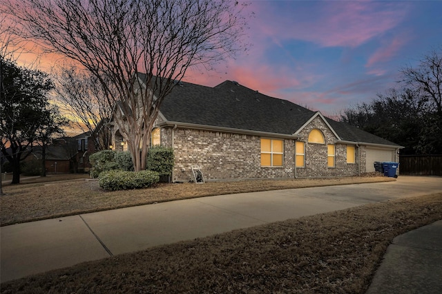 ranch-style home featuring a garage, concrete driveway, brick siding, and a shingled roof