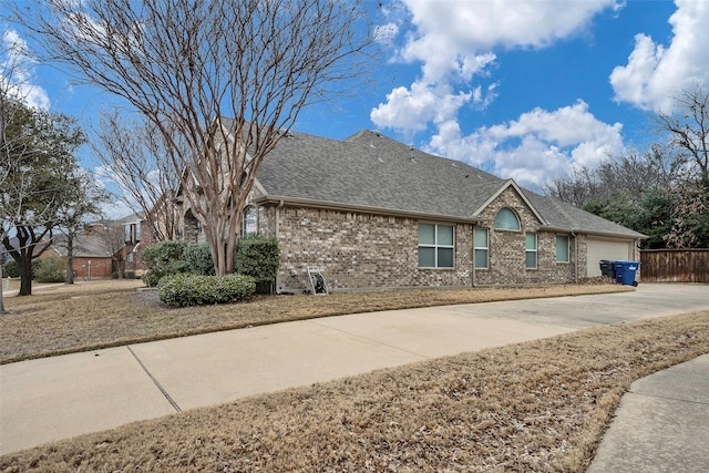 view of front facade with a garage, driveway, brick siding, and roof with shingles