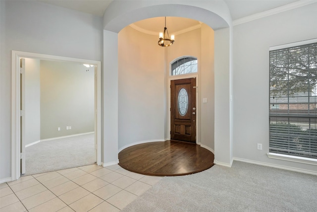 foyer with light tile patterned floors, baseboards, arched walkways, light colored carpet, and an inviting chandelier