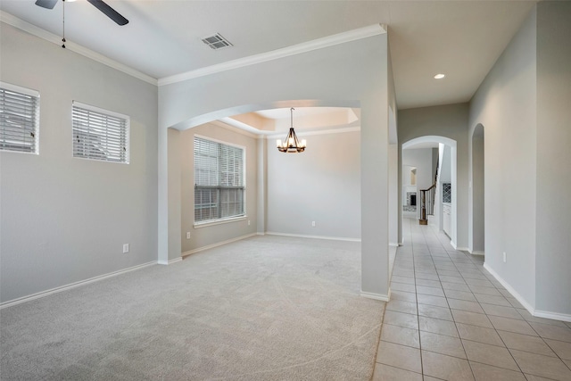 empty room featuring baseboards, visible vents, arched walkways, ornamental molding, and ceiling fan with notable chandelier