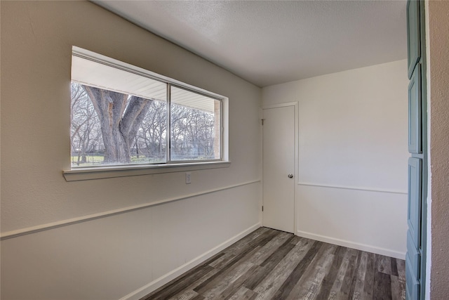 empty room with dark wood-style flooring and a textured ceiling