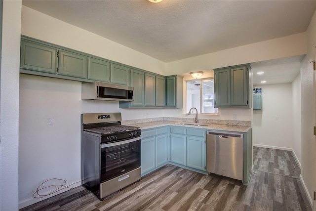 kitchen featuring dark wood-type flooring, baseboards, stainless steel appliances, and a sink