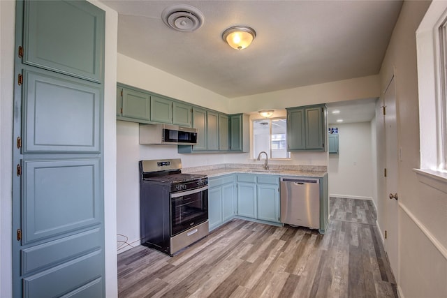 kitchen featuring stainless steel appliances, light countertops, a sink, and light wood-style flooring