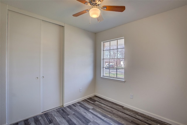 unfurnished bedroom featuring ceiling fan, a closet, dark wood finished floors, and baseboards