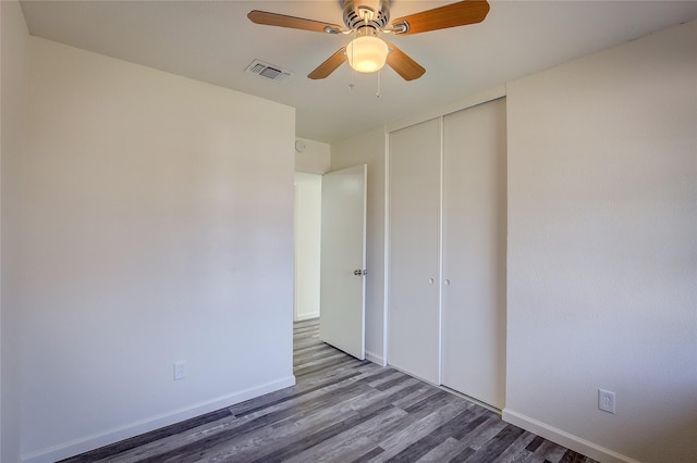 unfurnished bedroom featuring a closet, visible vents, baseboards, and wood finished floors