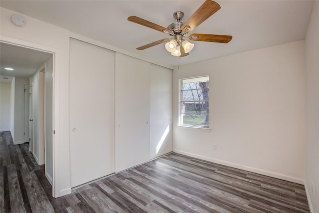 unfurnished bedroom featuring a ceiling fan, a closet, baseboards, and wood finished floors