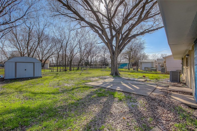 view of yard featuring an outbuilding, fence, a storage shed, and central air condition unit