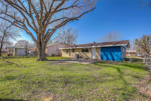 rear view of house with brick siding, a patio, a lawn, a gate, and fence