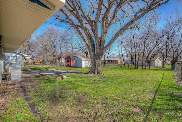 view of yard with cooling unit, an outdoor structure, fence, and a storage unit