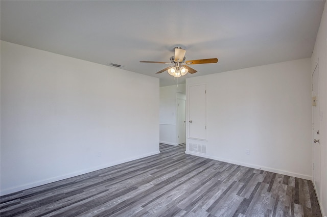 empty room with ceiling fan, wood finished floors, visible vents, and baseboards