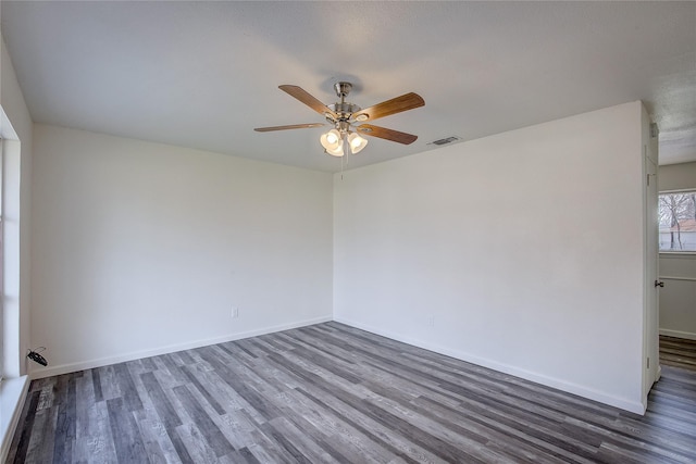 spare room with baseboards, visible vents, ceiling fan, and wood finished floors