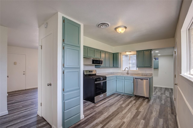 kitchen featuring visible vents, stainless steel appliances, dark wood-type flooring, and light countertops