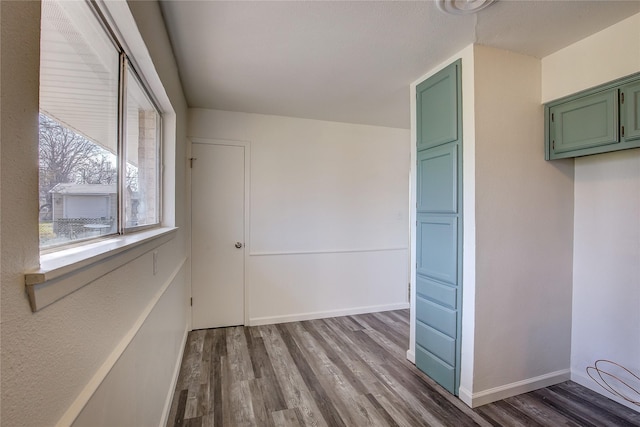 spare room with baseboards and wood finished floors