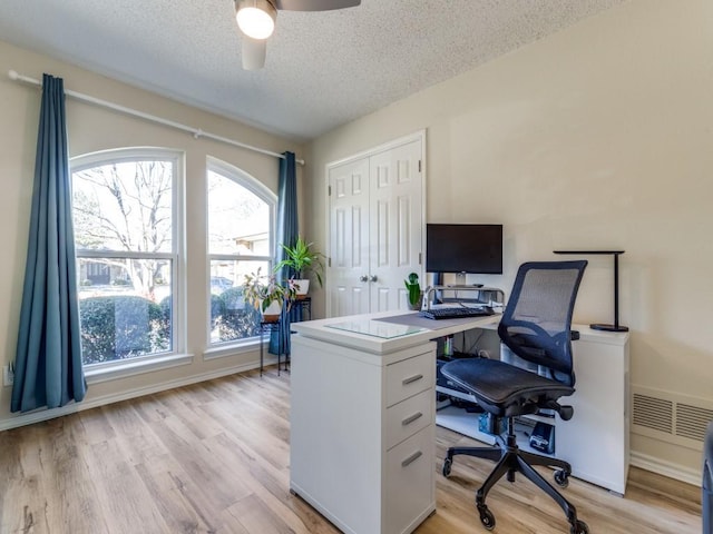 office featuring baseboards, visible vents, light wood-style flooring, ceiling fan, and a textured ceiling