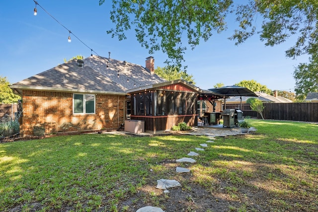 rear view of house with a lawn, a fenced backyard, a chimney, a patio area, and brick siding