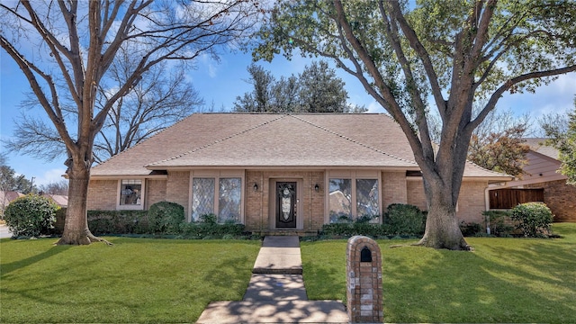 view of front facade featuring a front yard, brick siding, and roof with shingles