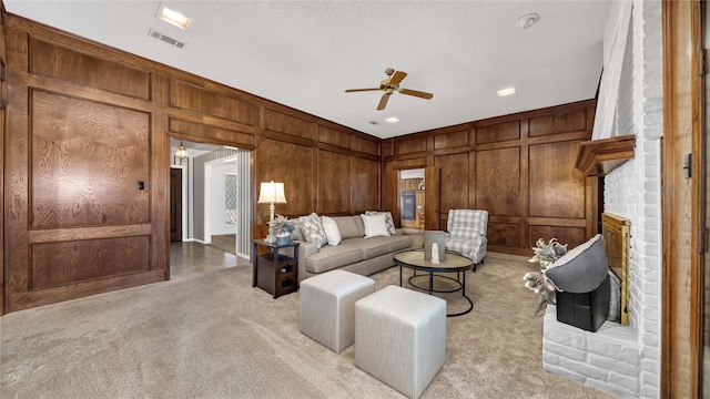 living room with light colored carpet, a decorative wall, visible vents, a brick fireplace, and wooden walls