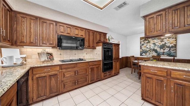 kitchen featuring visible vents, backsplash, brown cabinetry, light tile patterned flooring, and black appliances