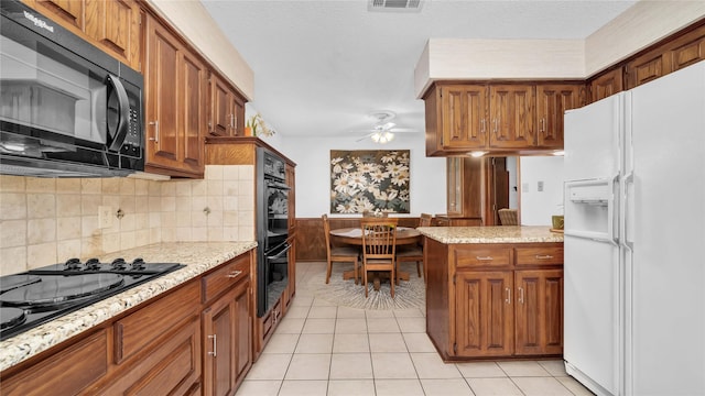 kitchen with brown cabinets, visible vents, light tile patterned flooring, ceiling fan, and black appliances