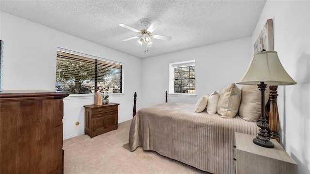 bedroom with ceiling fan, a textured ceiling, and light colored carpet