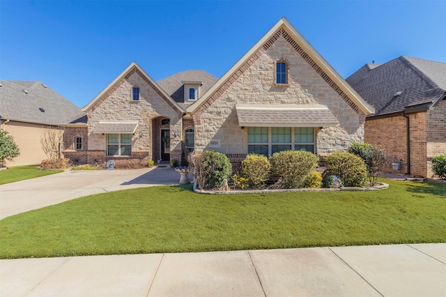 french provincial home featuring stone siding, brick siding, and a front yard